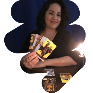 A Taróloga está com quatro cartas de na mão mostrando alegremente sob a luz de velas.
